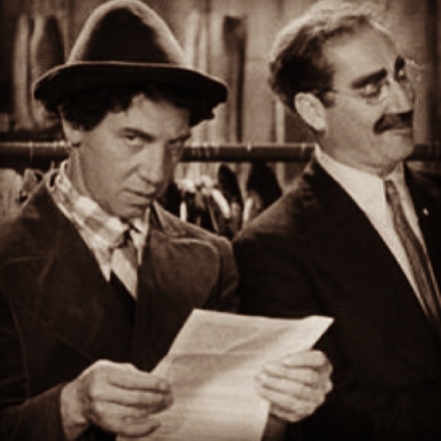 two men dressed in business clothes one reading a piece of paper