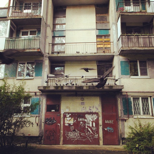 a dilapidated multi - story building with many windows and a balcony