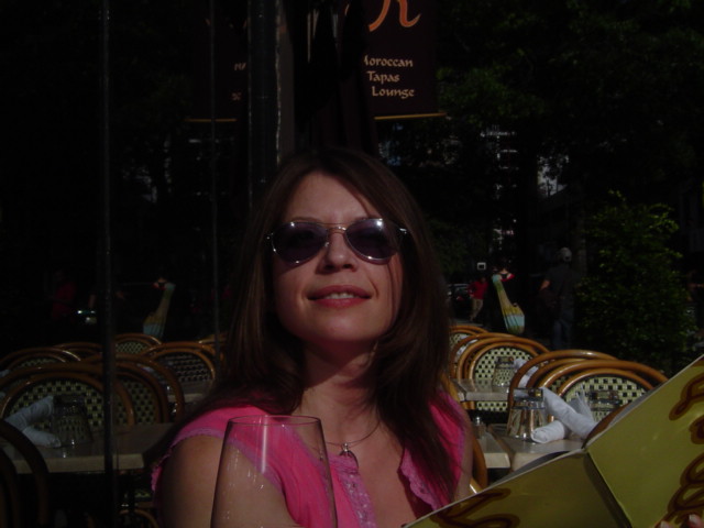 a woman in sunglasses is sitting at an outdoor restaurant