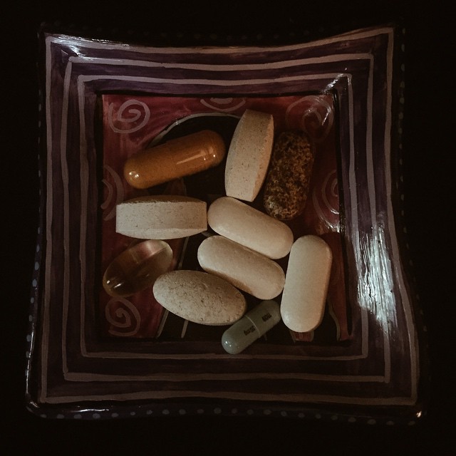 a glass bowl filled with assorted pills on top of a wooden table