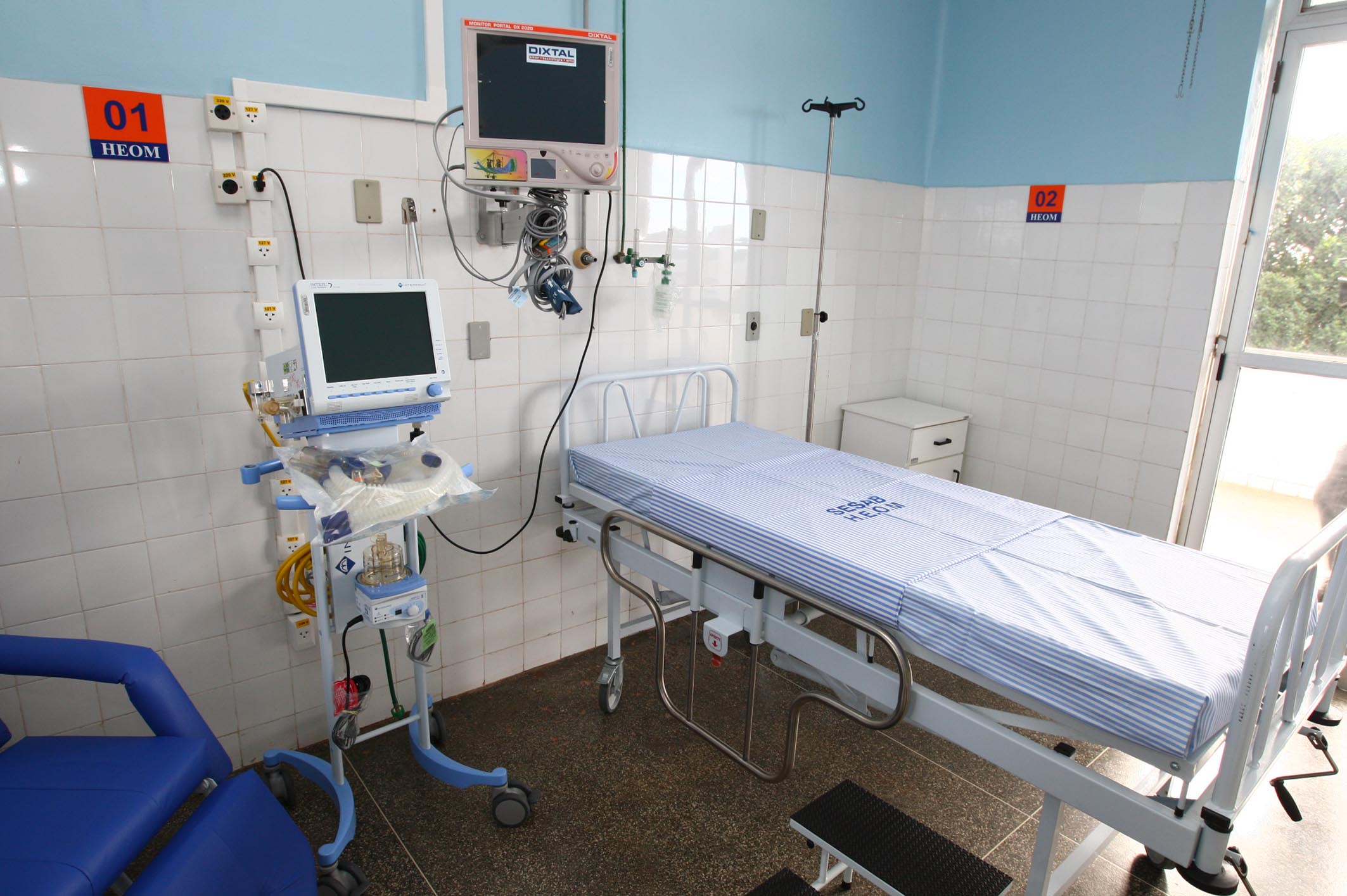 an empty hospital room with blue walls and equipment
