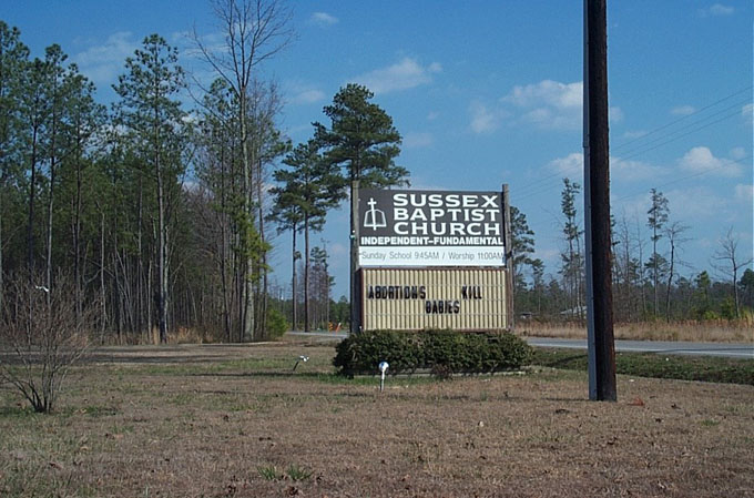 the street sign for sussex baptist church with an intersection beside it