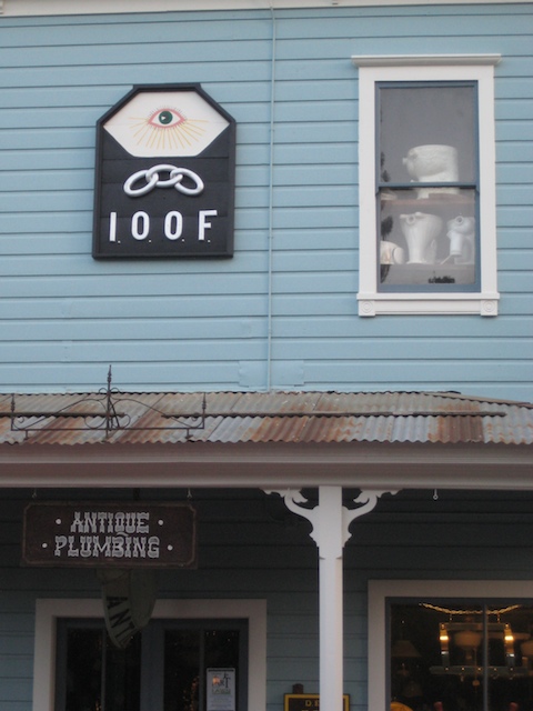 a blue building with an antique plumbing sign and a teddy bear