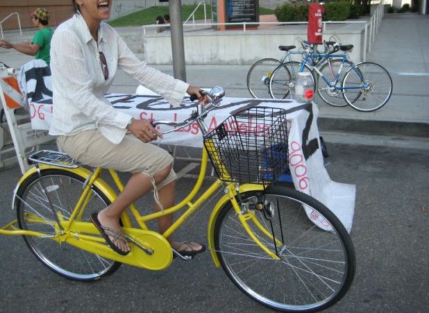 the woman smiles while riding her yellow bike