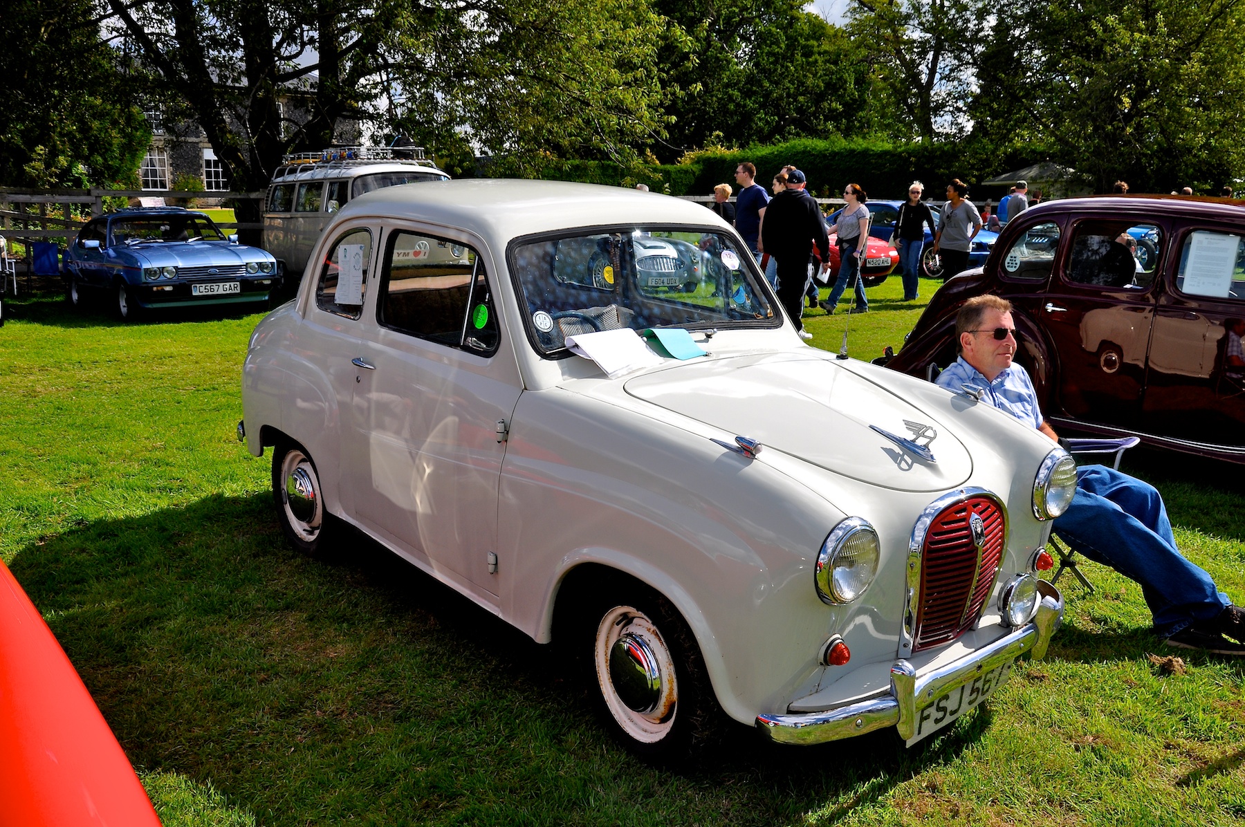 a man sitting on the side of a white car in a field