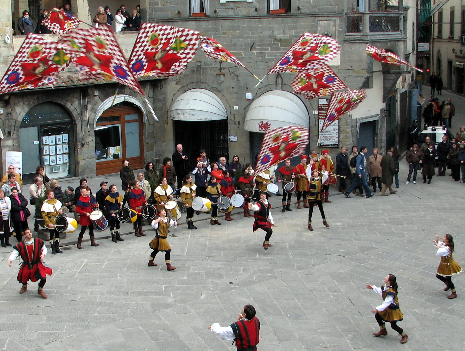 a group of people wearing costumes and holding colorful flags