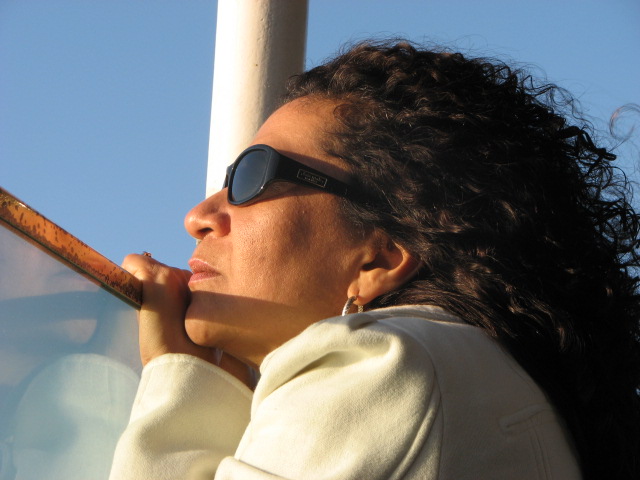 woman in sun glasses sitting on a bus while holding a bat