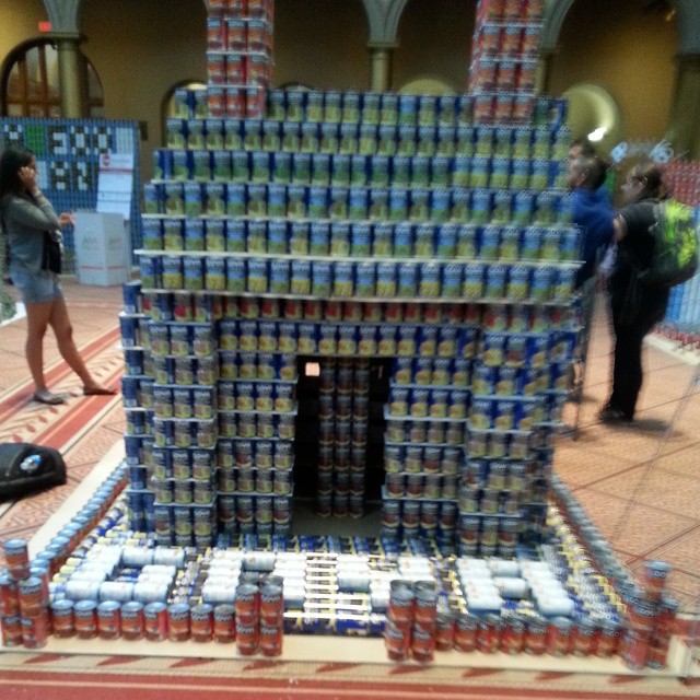 people standing next to a structure made out of cans