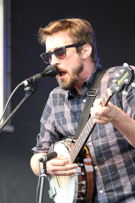 a man holding an ornate guitar at an outdoor concert