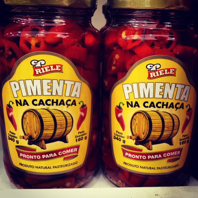pickled red peppers sit next to canned pinenta na cachiacaa in jars
