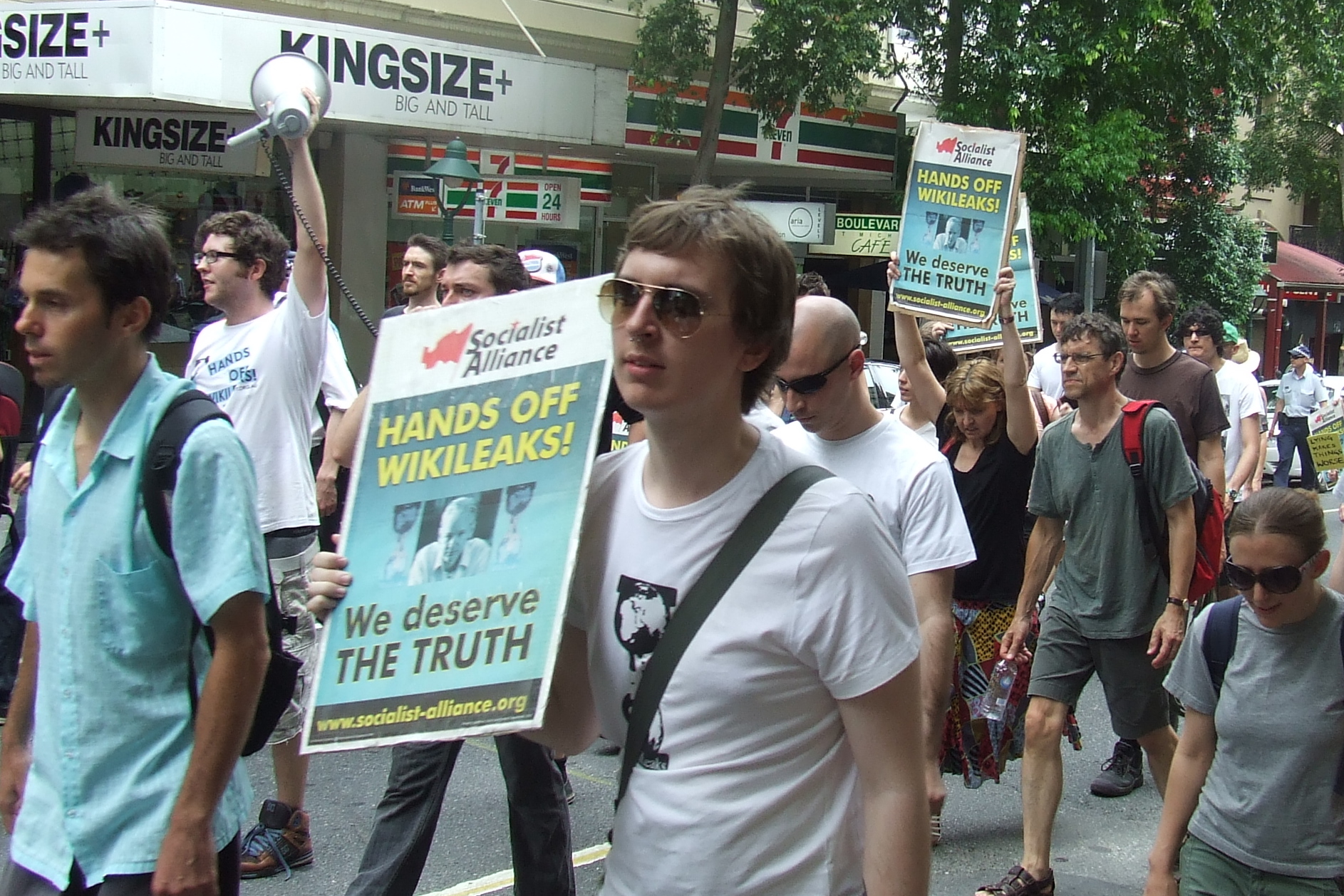 a crowd of men walking down a street holding signs