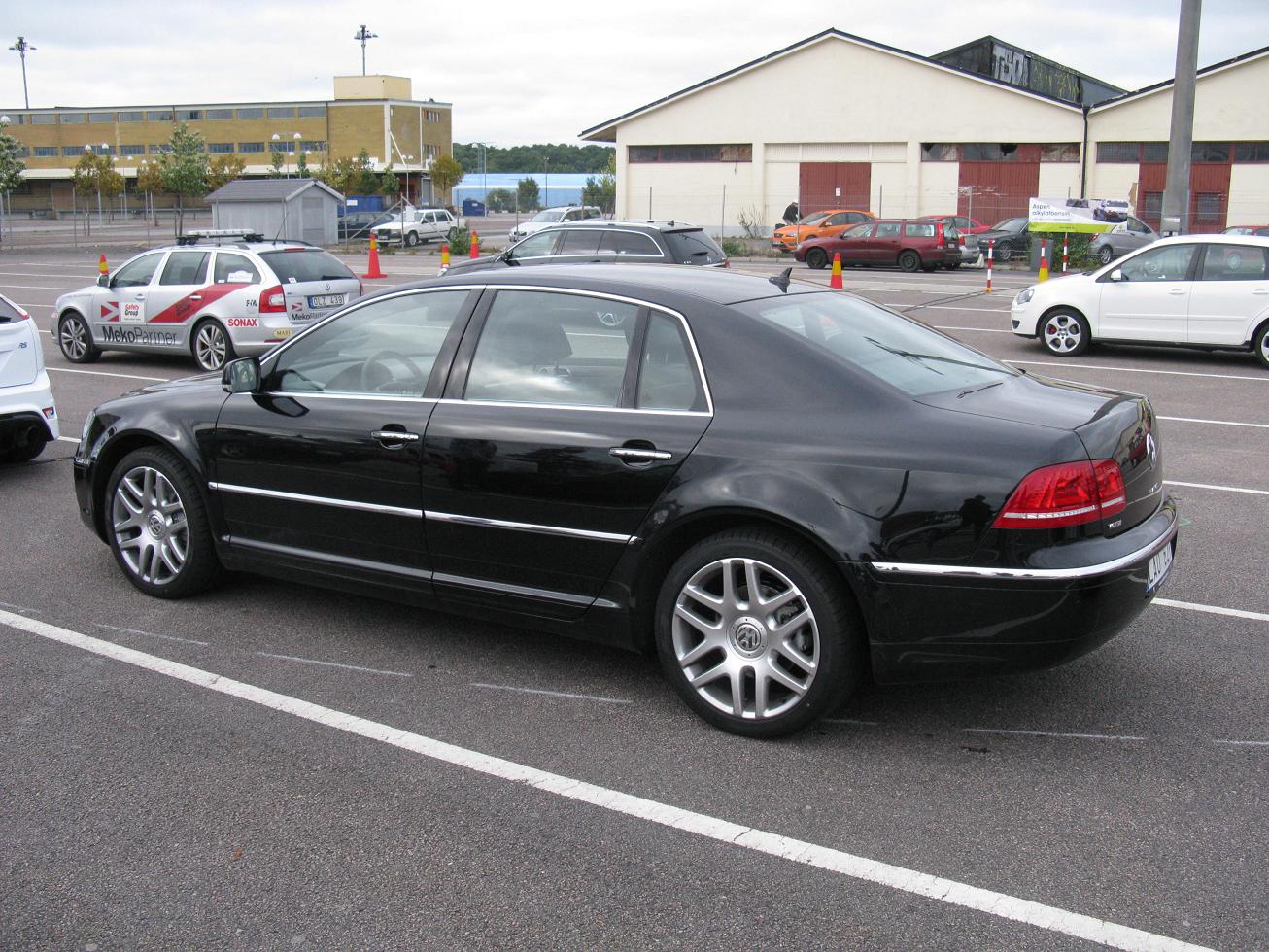 black mercedes parked in parking lot with several cars in the background