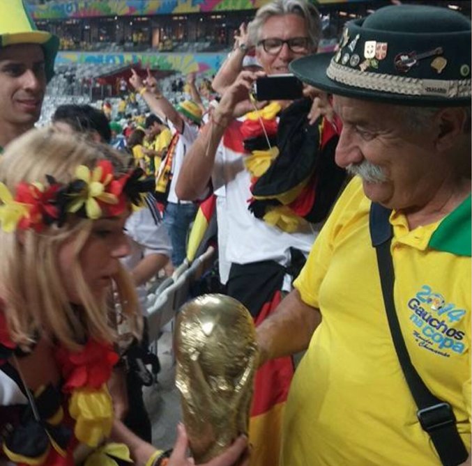 two women are holding the world cup and watching a soccer game