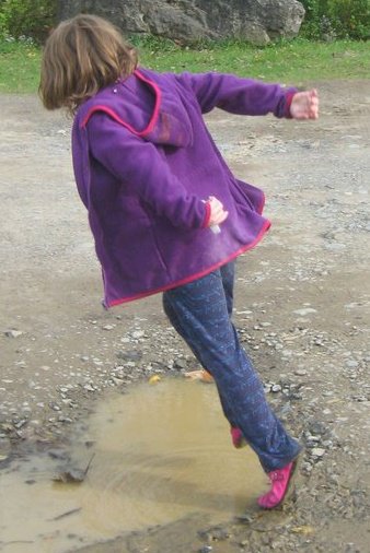 a little girl playing in the mud in the park