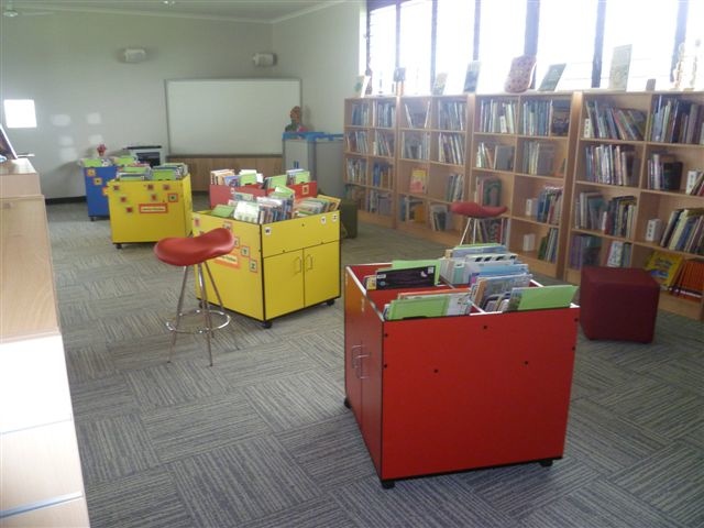 a large liry with tables, chairs, a whiteboard and many books