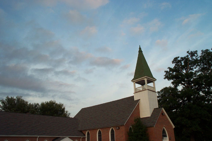 a church on a hill at dusk with blue sky