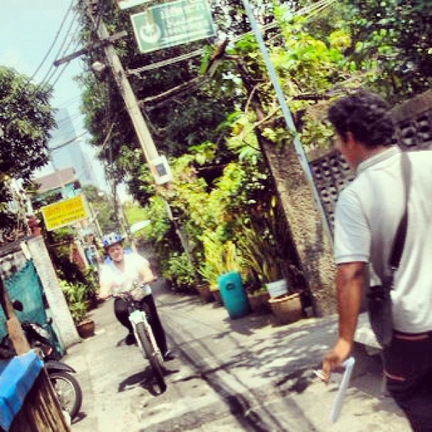 two men are riding motorcycles on a narrow road