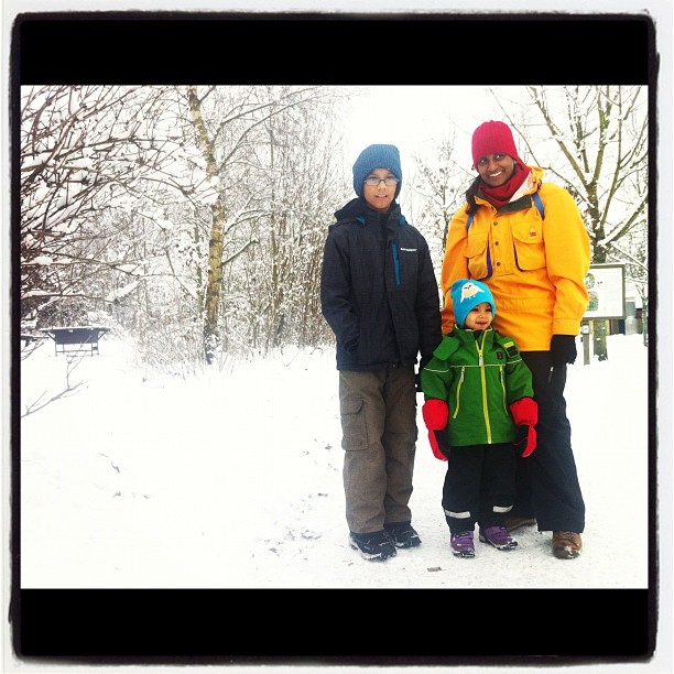 a man and two boys standing in the snow in the woods