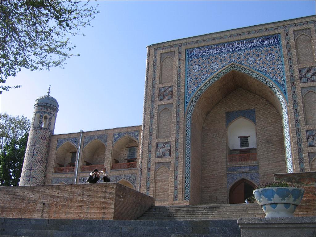 a woman walking across a stone walkway in front of a building