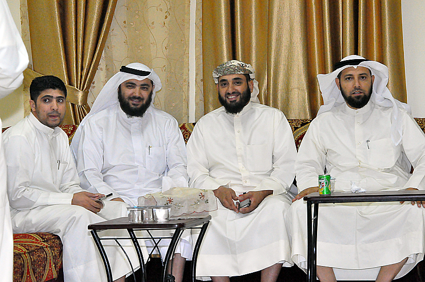 three men in white sitting on top of a chair