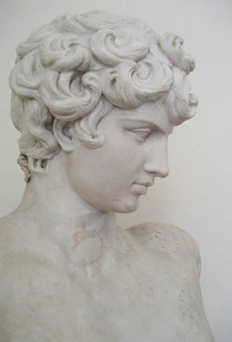 a marble bust sitting next to a white wall