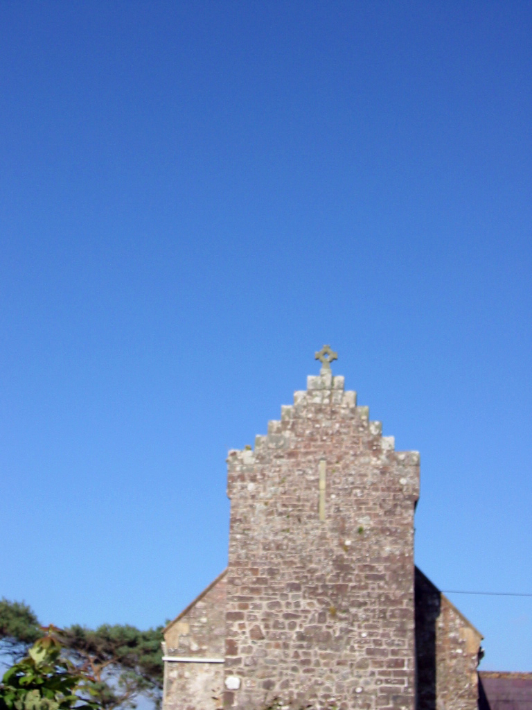 old, stone church structure in town square setting on blue sky