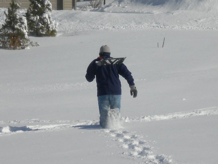 a person standing in the snow carrying a ski pole