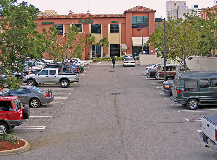 a person is walking in the parking lot with several parked cars