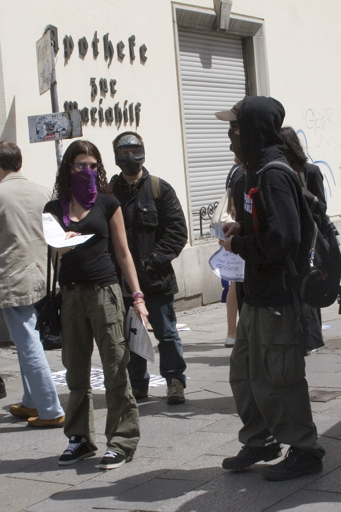 a group of people in masks standing on a sidewalk