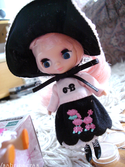 a doll wearing a black hat is on a fur