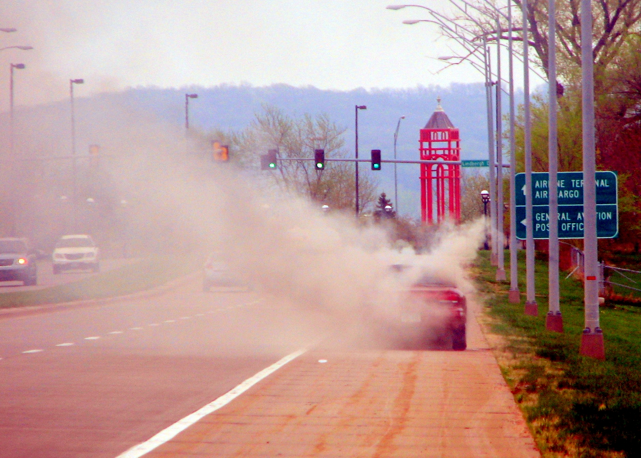 a car driving down a street, with smoke coming out of it