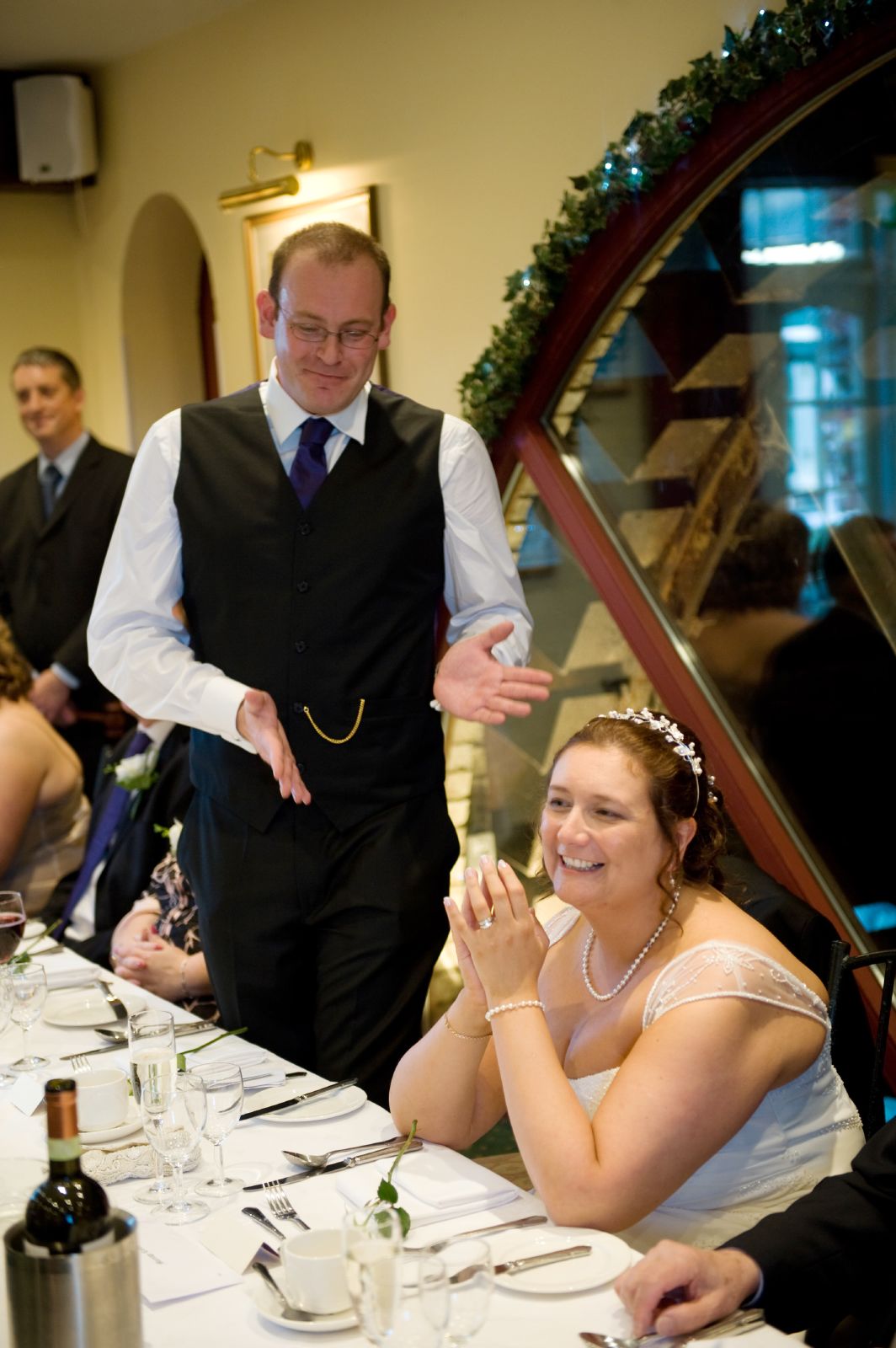 a man is standing behind a bride who is sitting down at a table