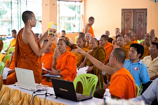 a group of monks with laptops and books in a room