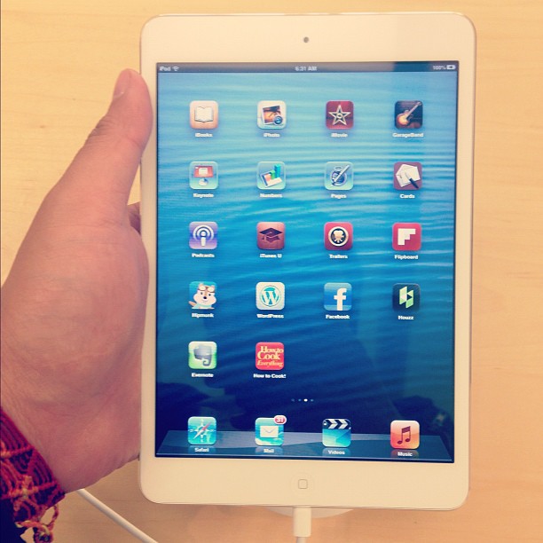 an ipad being held up by someone with an earphone