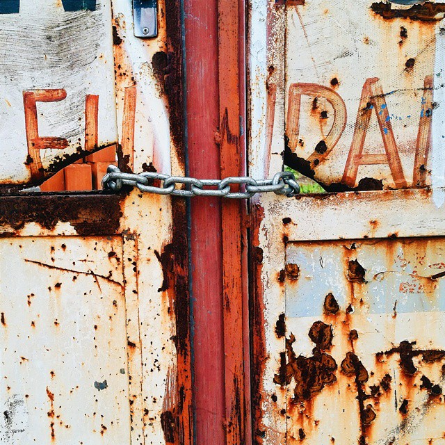 a rusted steel door that has a chain hanging out of it