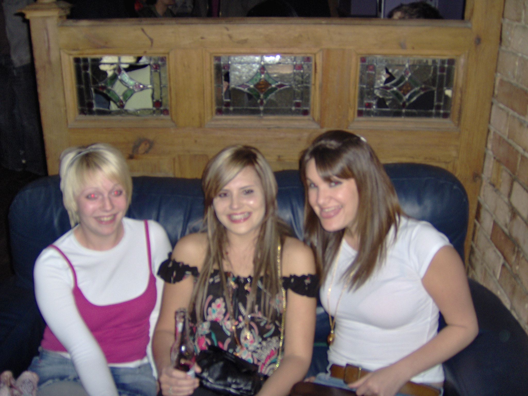 three women sitting next to each other on top of a couch