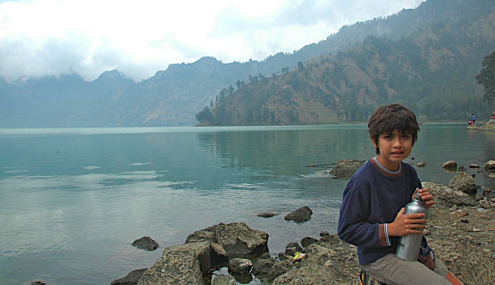a young man holding a can with the mountains in the background