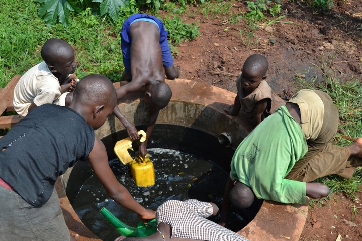 people in an outdoor water well are gathered around the man