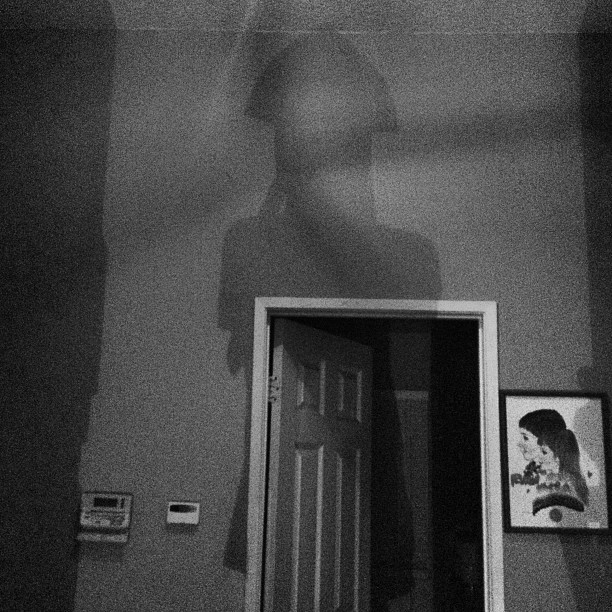 a person in black and white shadow looking down a doorway
