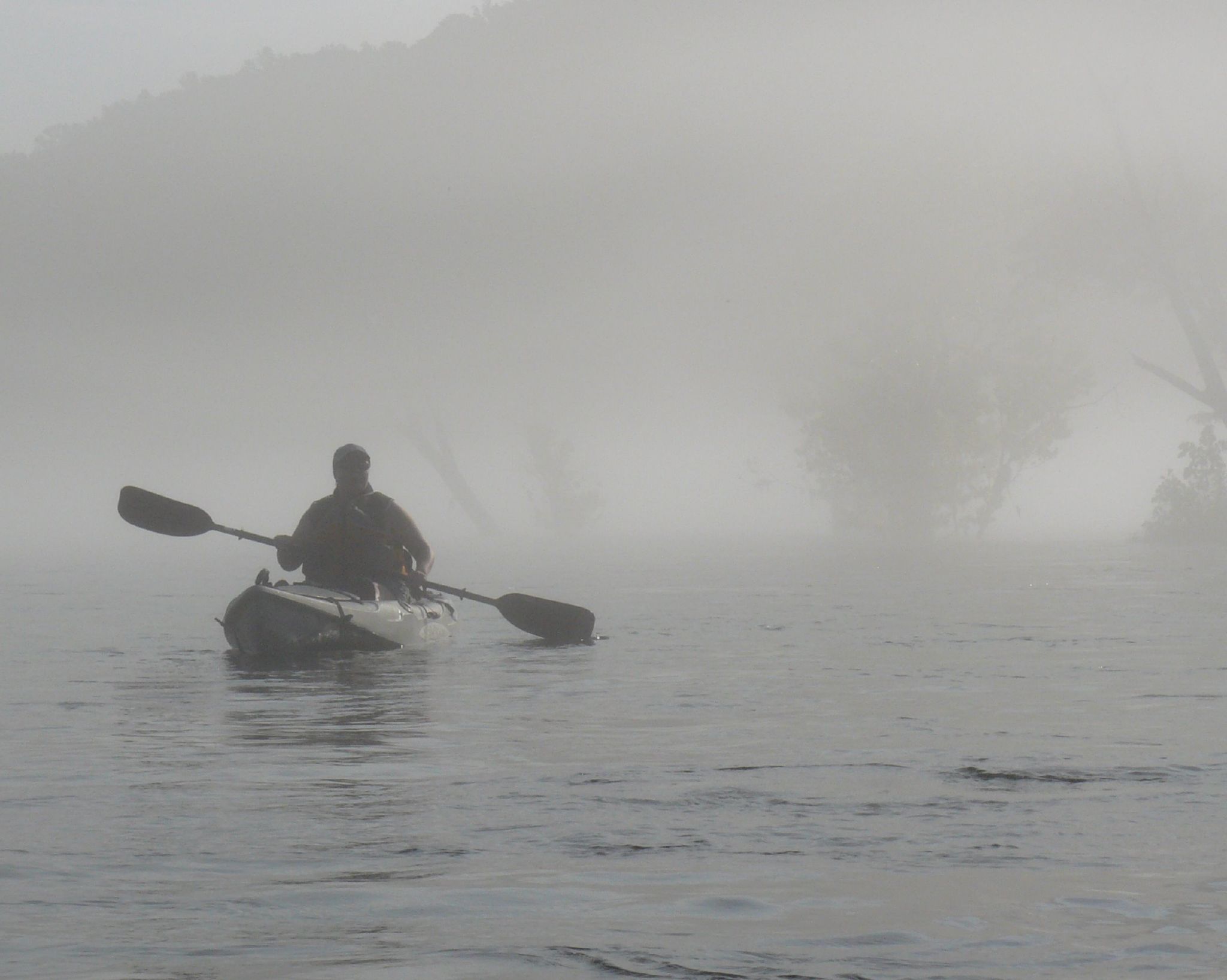 the man is paddling his kayak through the foggy water