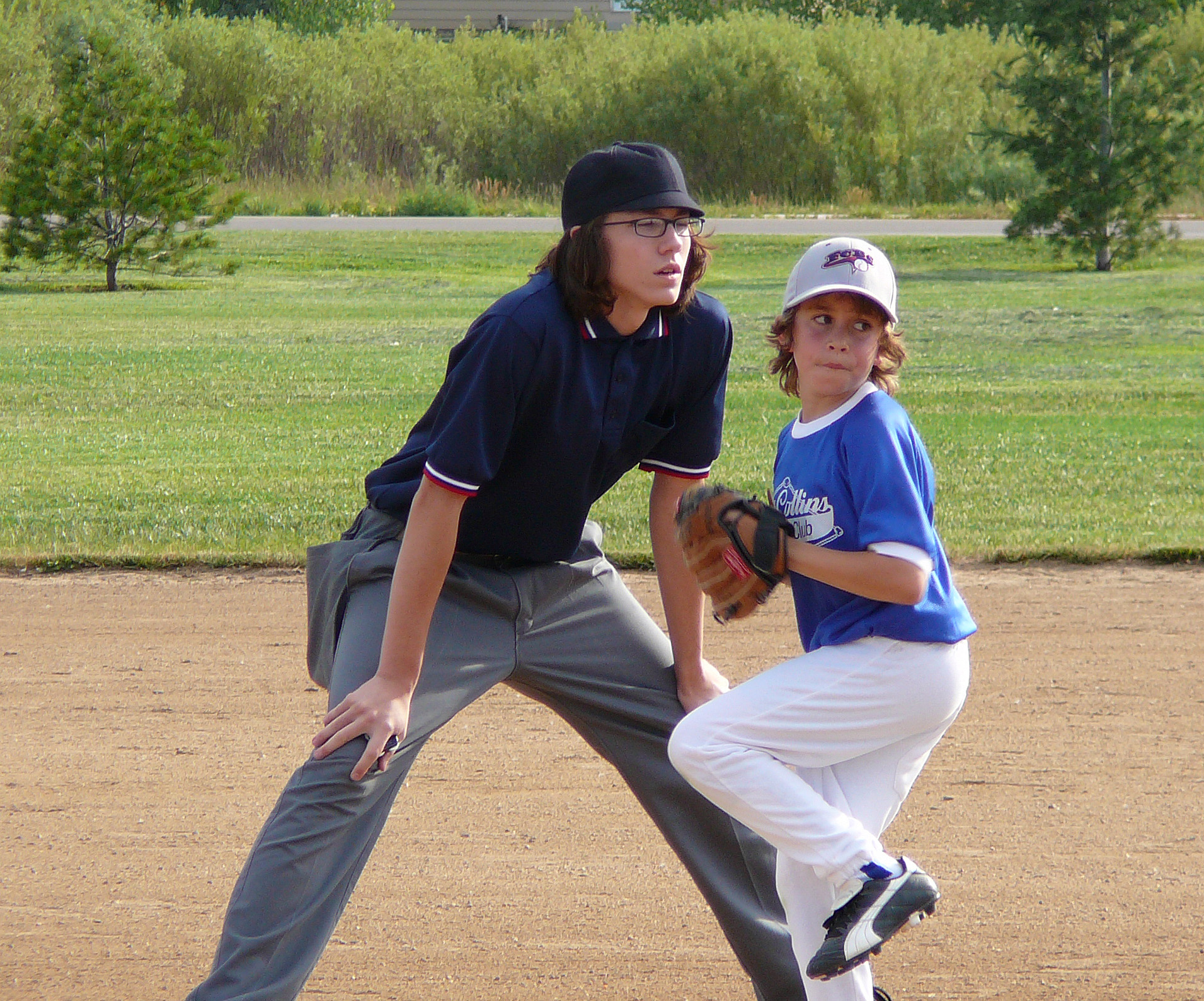 two children play baseball on a dirt field