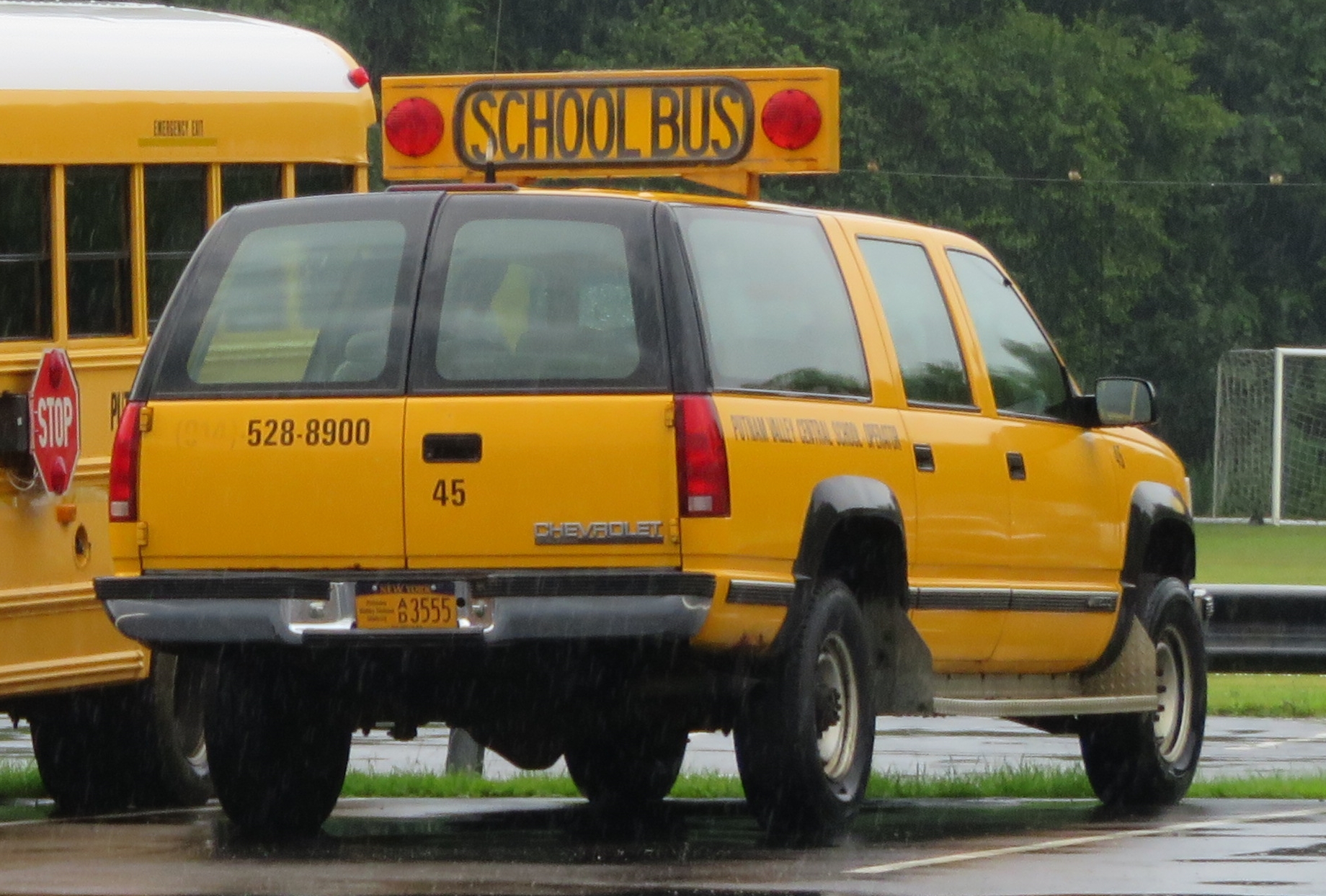 two school buses parked on the side of a road in the rain