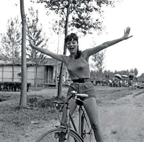 the woman is standing on top of her bike