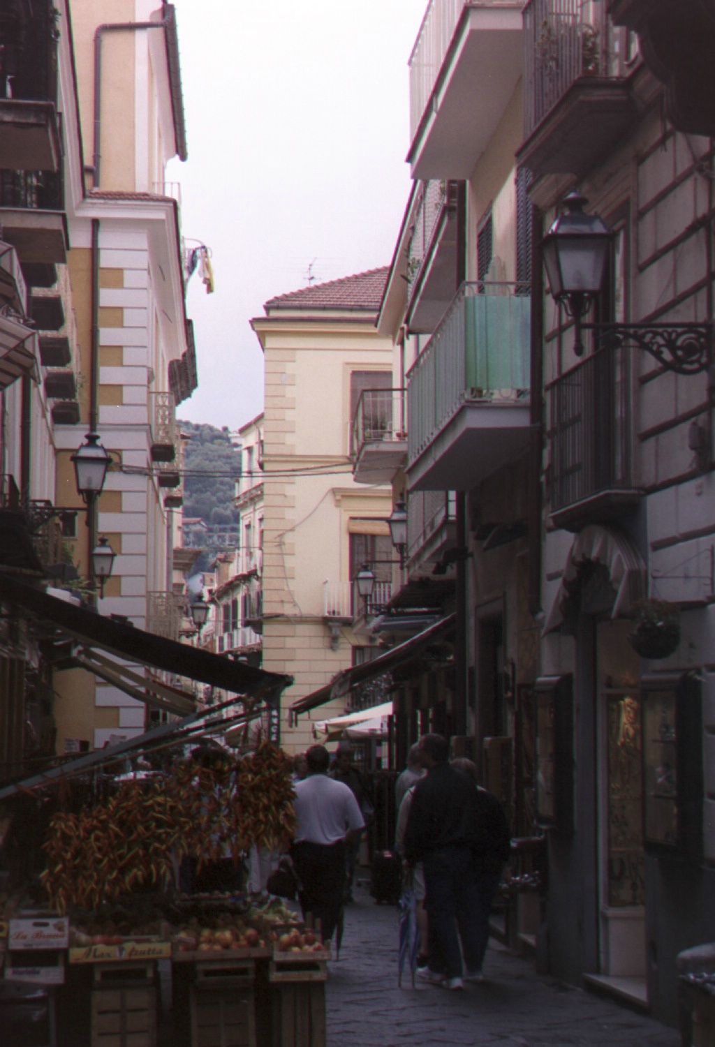 an alley in a city with lots of old buildings and people walking