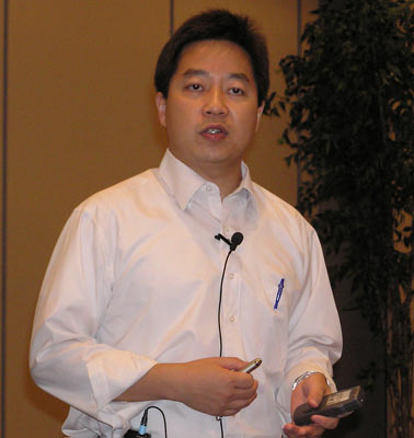 an asian man holding a phone and looking at the camera