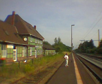 man in white shirt standing near a train station with buildings