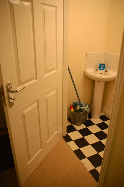 a bathroom door is open with a mop in the bucket