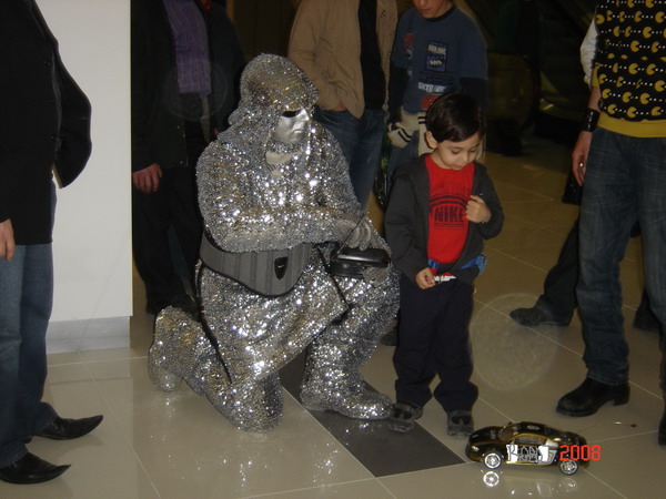 a little boy standing next to a silver gorilla statue