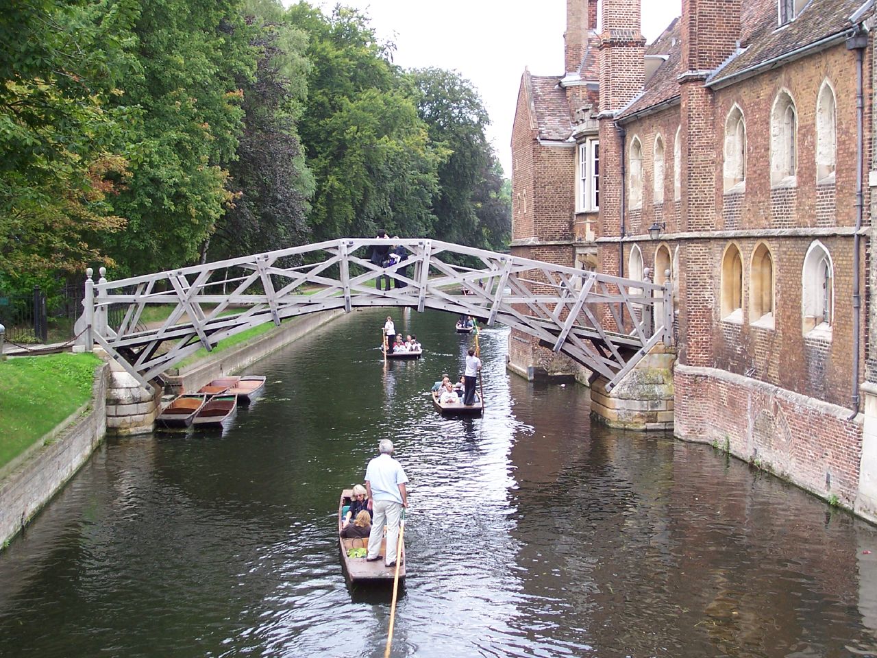 several boats float under an arched bridge on the river
