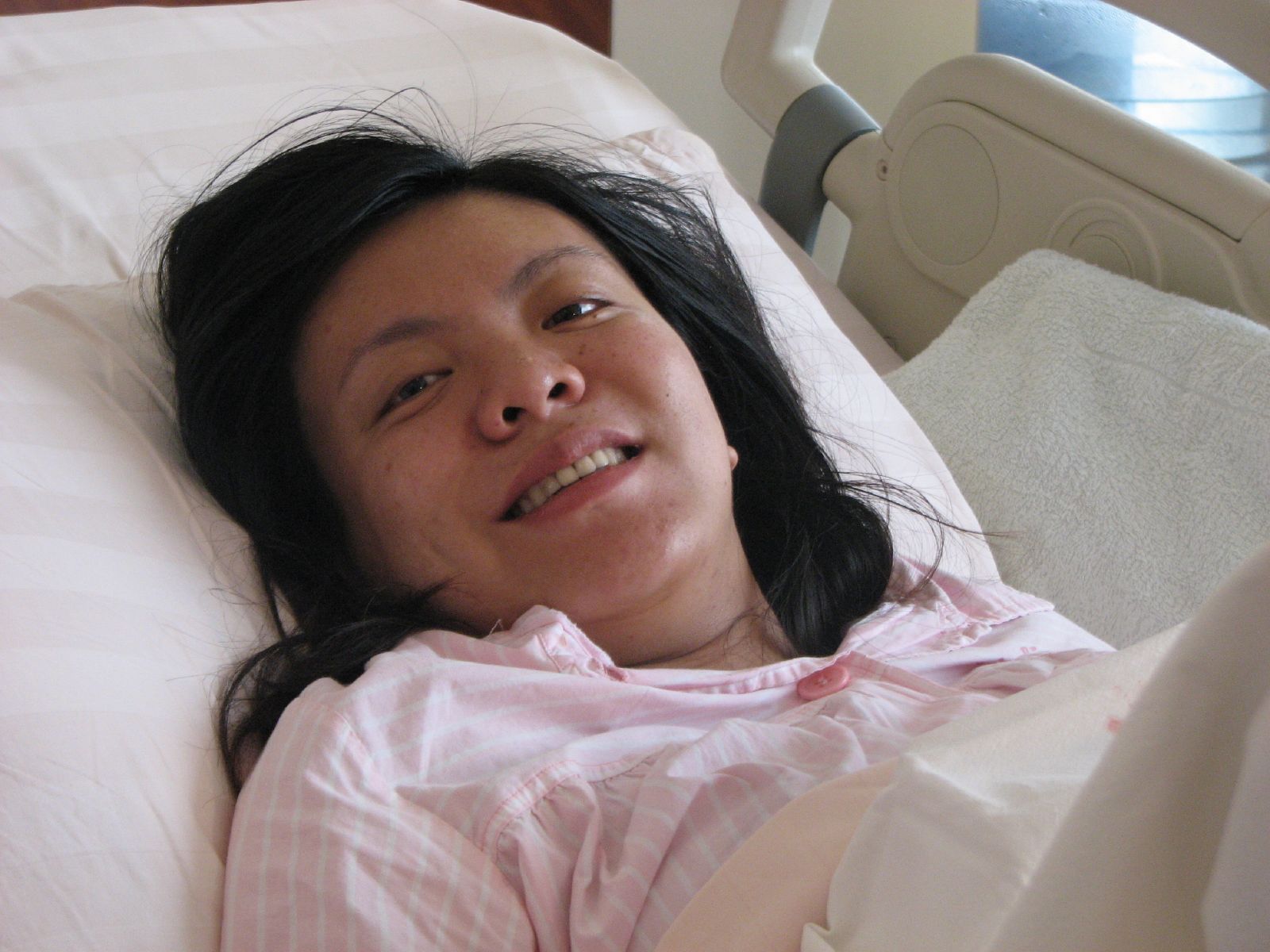 a young asian woman in hospital bed smiling